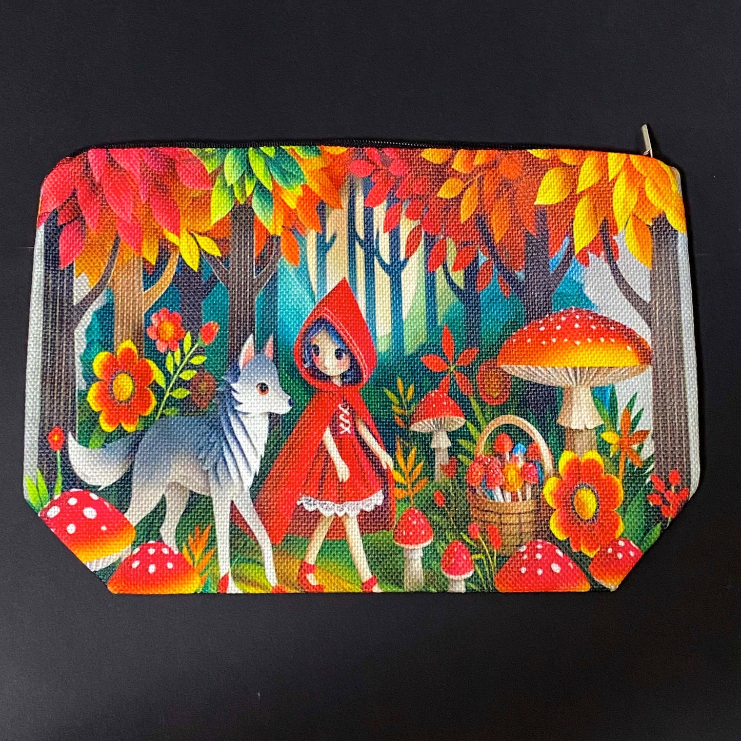 little red riding hood themed canvas zip pouch featuring colourful woodland mushrooms, autumn trees, flowers and a grey wolf companion in a storybook forest scene. red, orange, yellow and lime green colourful gift bag.