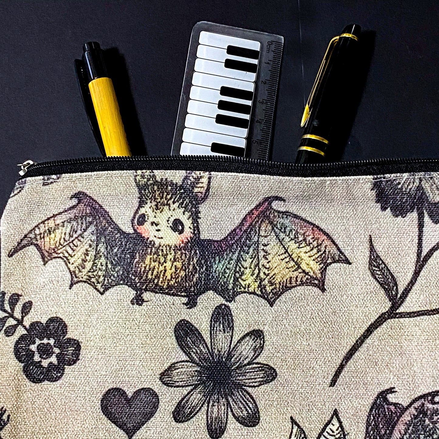 canvas taupe brown zip pouch featuring dark rainbow coloured flying bats and botanical illustrations, presented with kraft belly band and wax seal sticker. uk letterbox gifts shop.