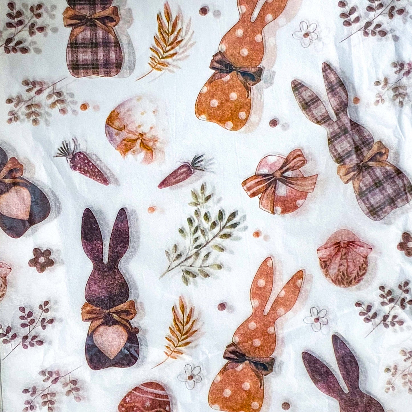 tissue paper sheets with pattern of brown and natural rabbits, carrots, and flowers on a white background