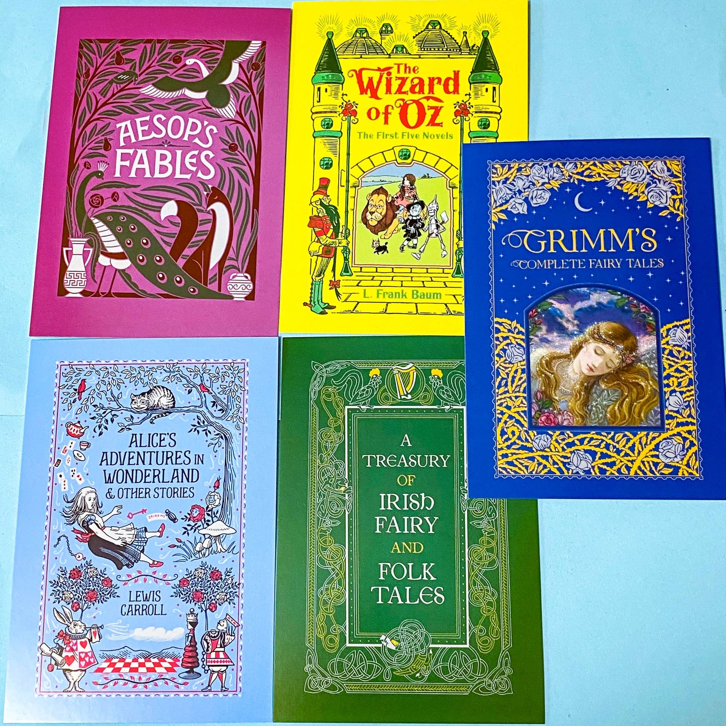 set of 5 vintage literary postcards featuring fairytale book covers including Alice in Wonderland, Wizard of Oz, irish folk tales, aesop fables and Grimm Fairy Stories on a blue Background