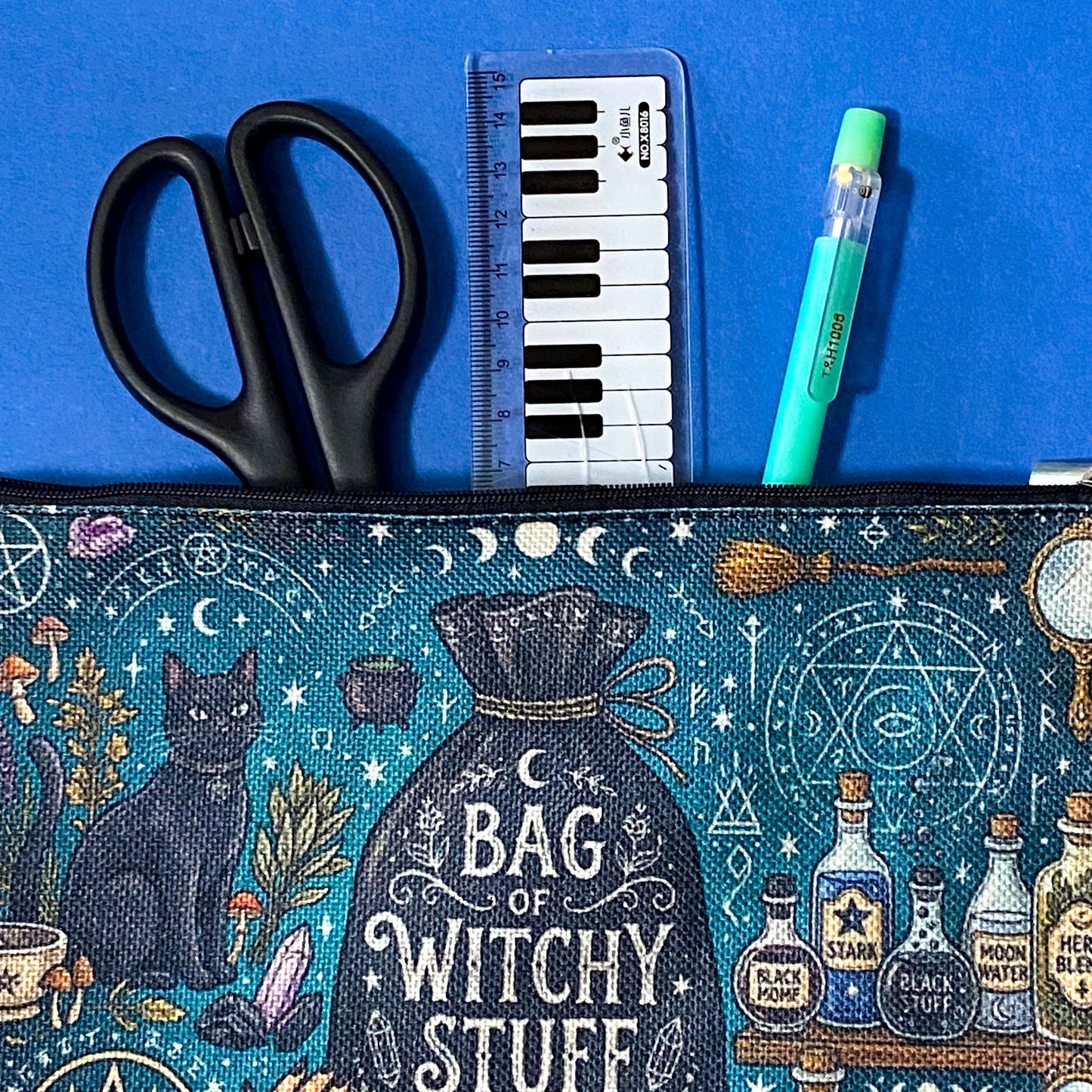black cat apothecary zip pouch featuring witchy illustrations including a black cat potion bottles, crystals, herbs and moon phases. Teal and black fabric cosmetic bag.