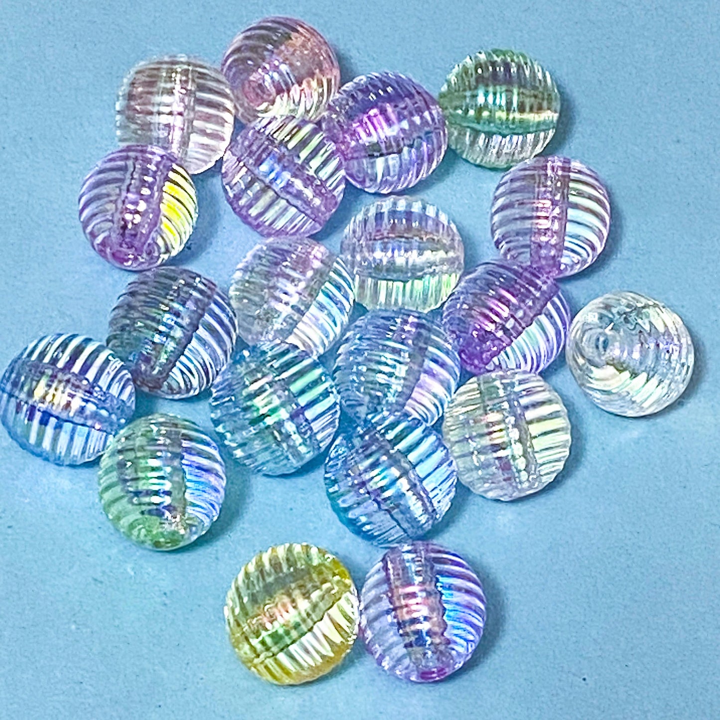 Multi-coloured striped or ridged 16mm acrylic blear round beads on a blue background