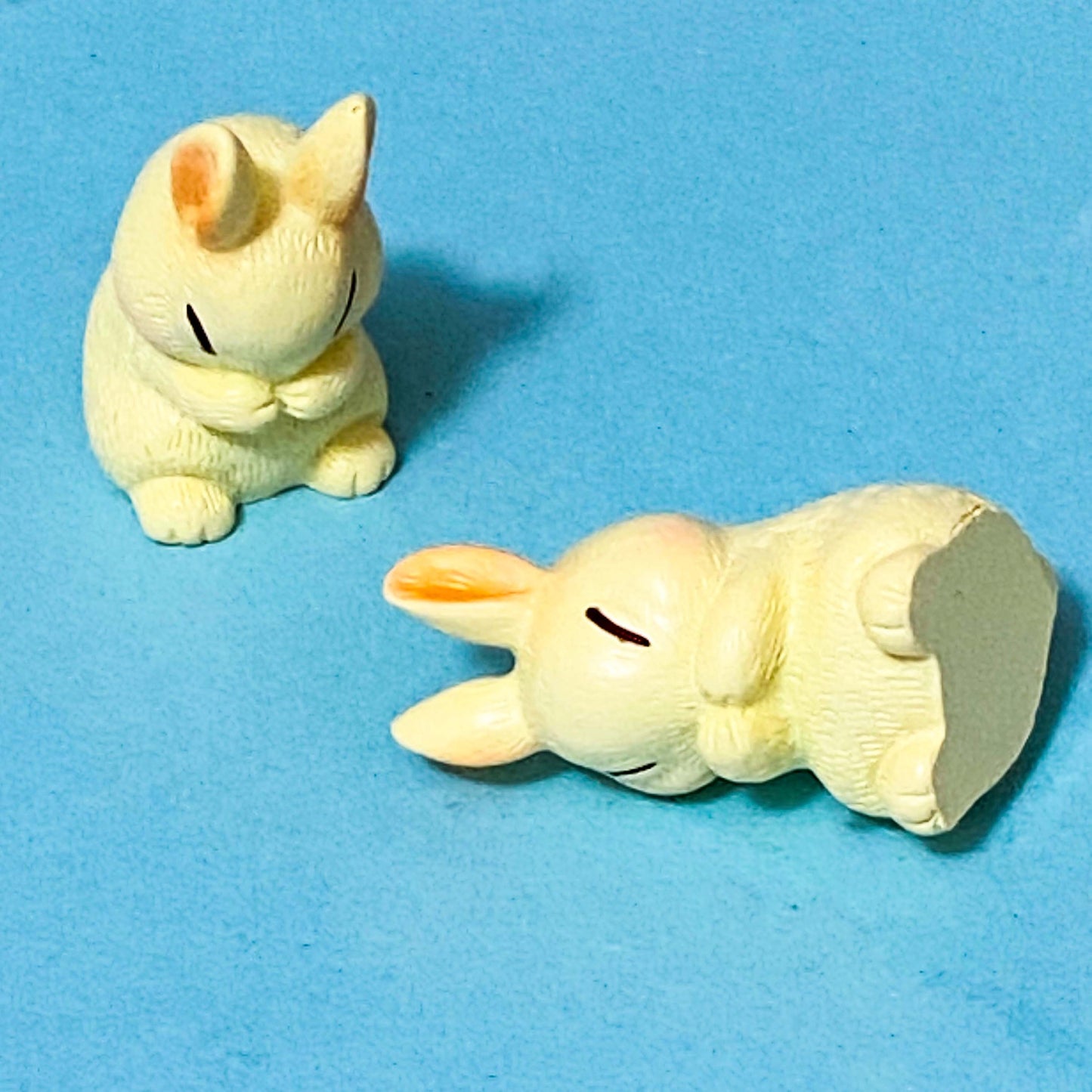 Two small rabbit cute animal figurines on a blue background