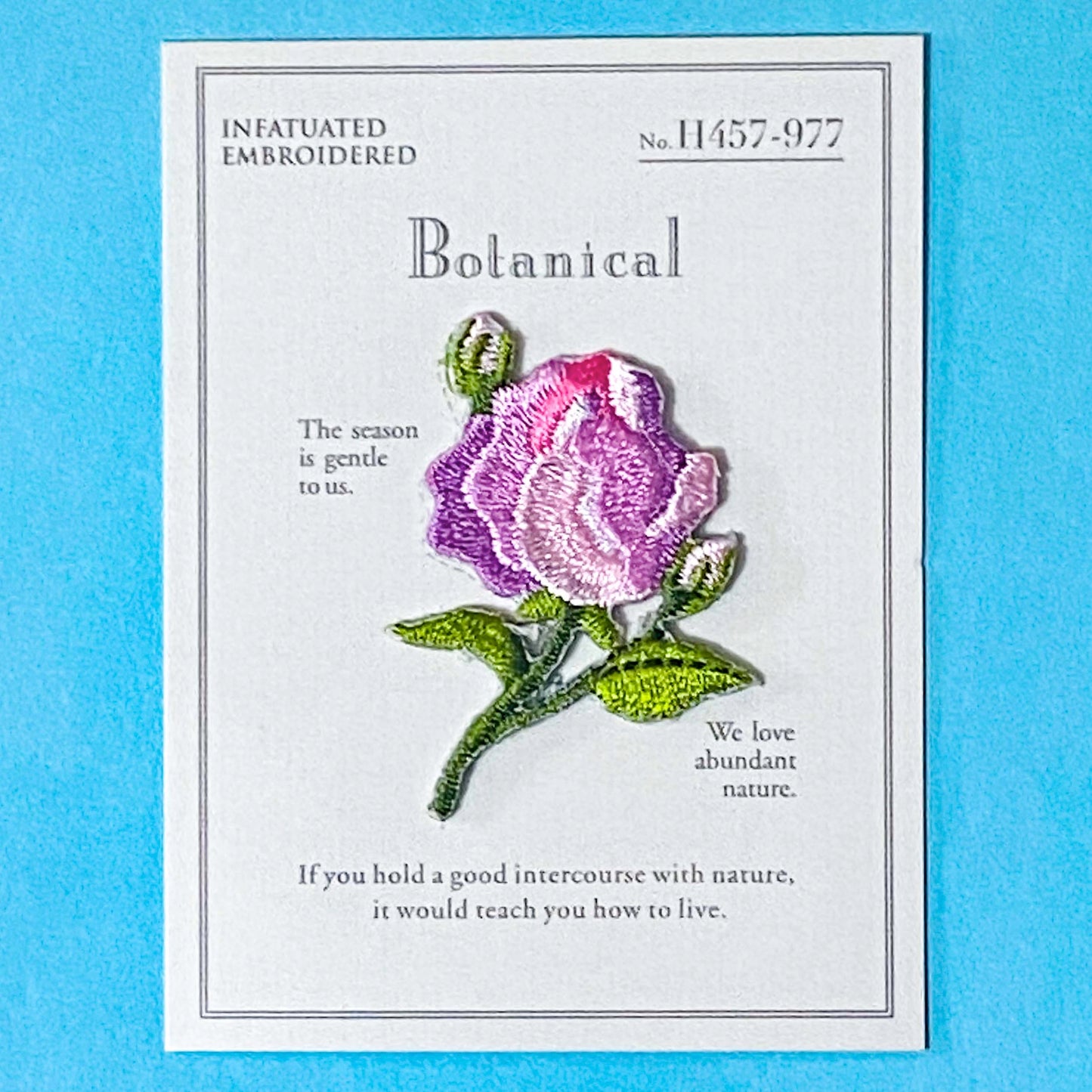 pink rose embroidery iron on patch on a blue background
