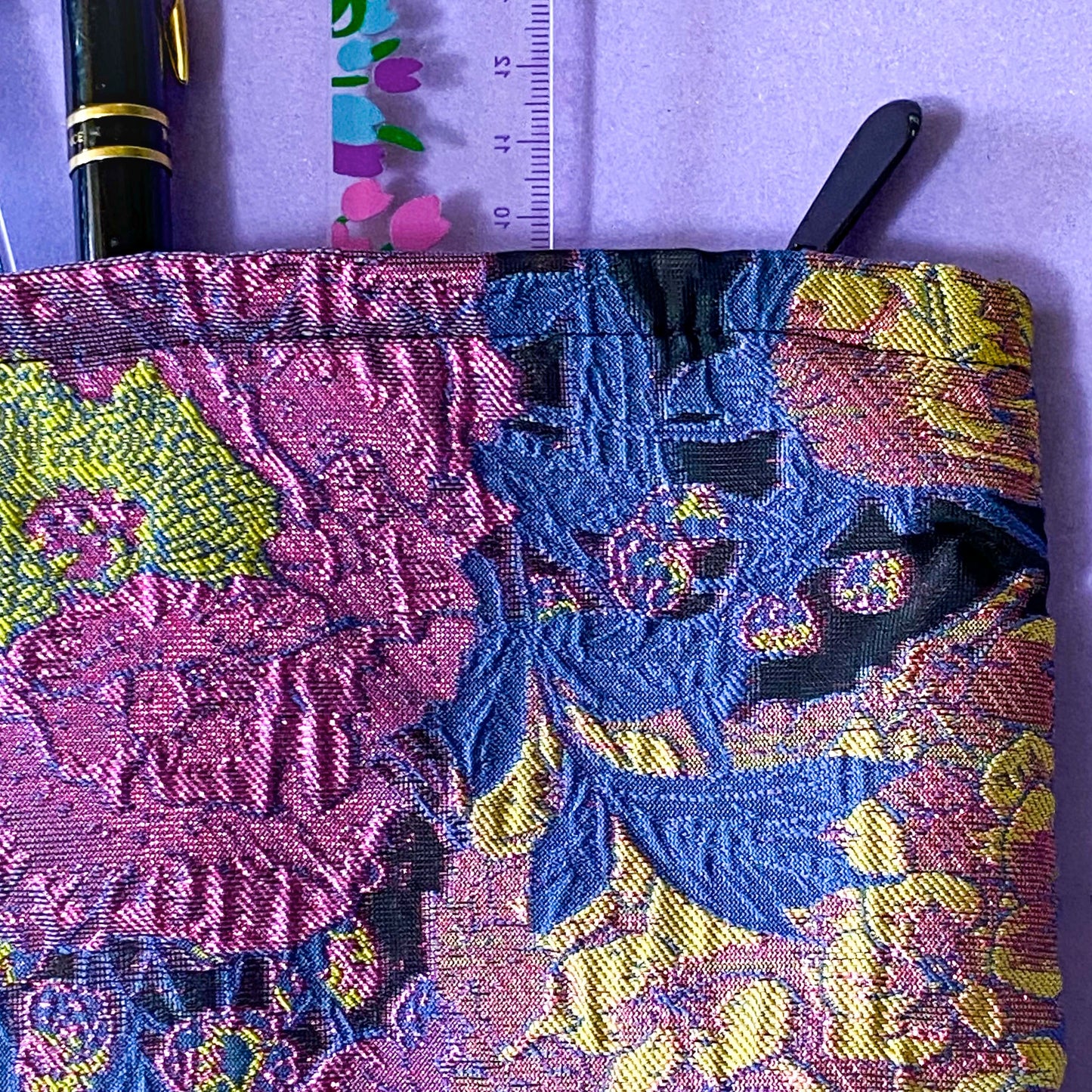 sapphire and magenta twilight luxury woven tapestry cosmetic or jewellery pouch with a sapphire blue botanical leaves and vibrant cerise florals. fully lined in black fabric and finished with a concealed zip.