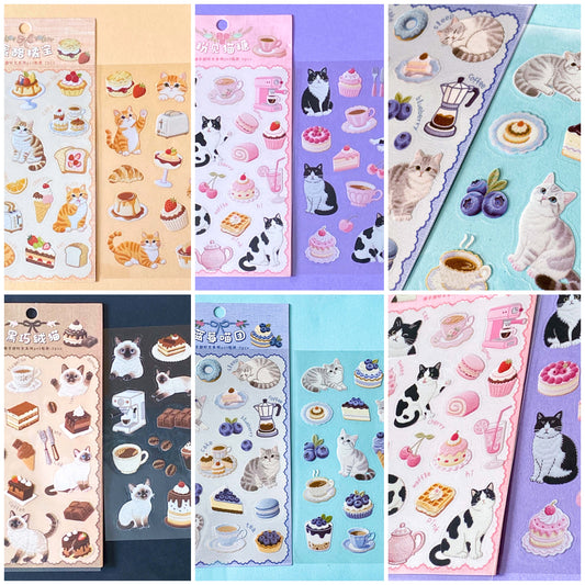 sticker packs of 2 clear PET sheets with cute cat stickers and edible cakes, sweets and treats. Cafe themed cats with tuxedo cat, siamese, grey tabby and ginger kittens. ute foods including fruit desserts.
