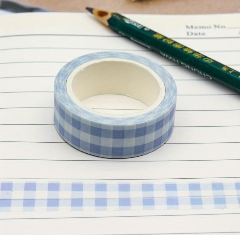 Roll of blue checkered tape on a piece of lined paper with a pencil.