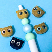 flocked brown cat face beads on a beaded pen on a blue background
