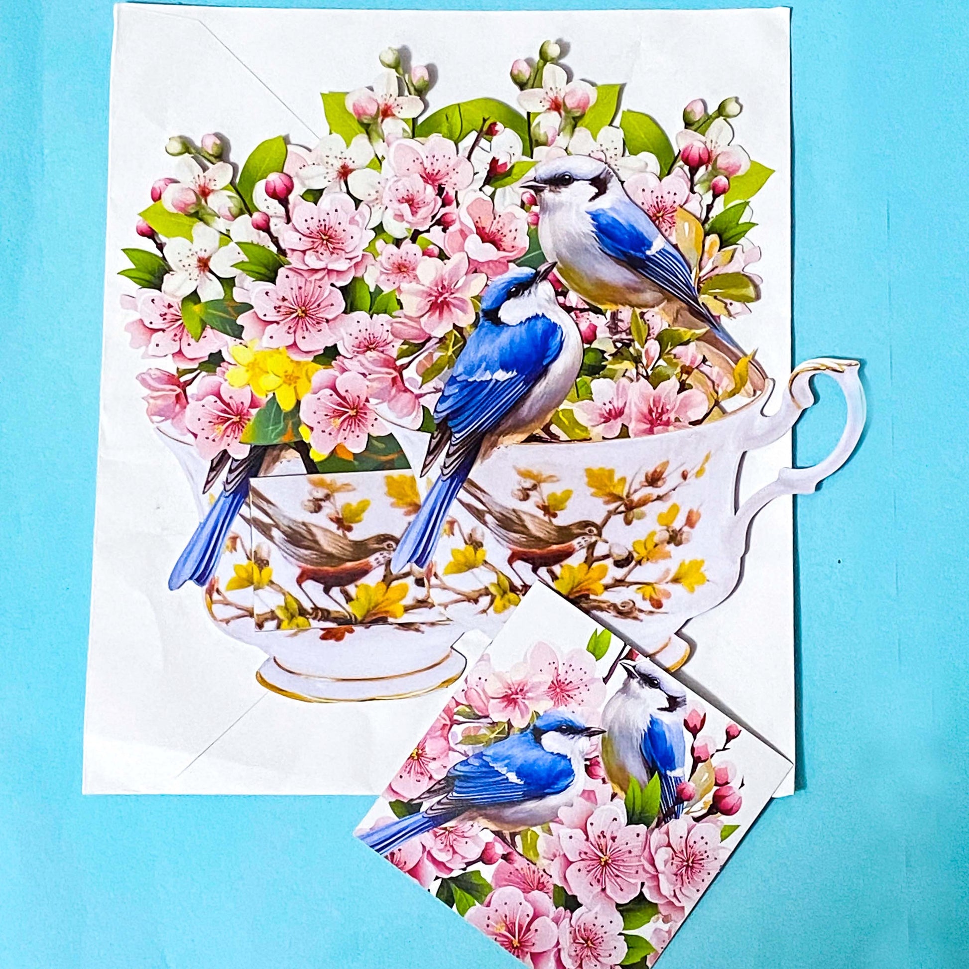 3d pop up card with blue birds and pink cherry blossoms in a tea cup on a blue background
