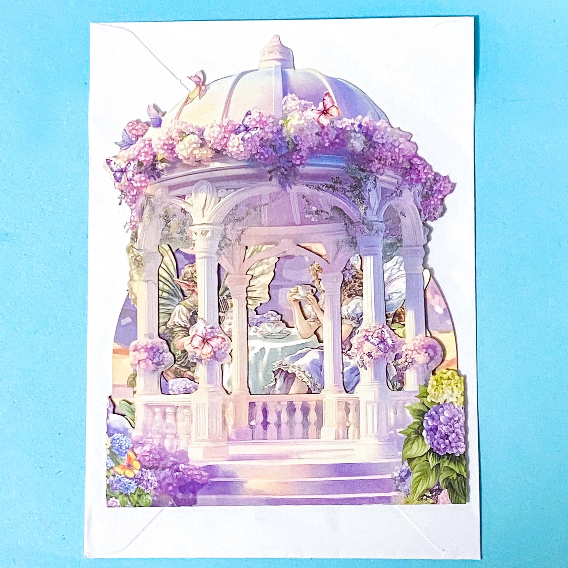 Decorative card with a fairy in a gazebo surrounded by flowers on a blue background