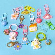mixed bundle of resin and metal bag charms and keyrings on a blue background