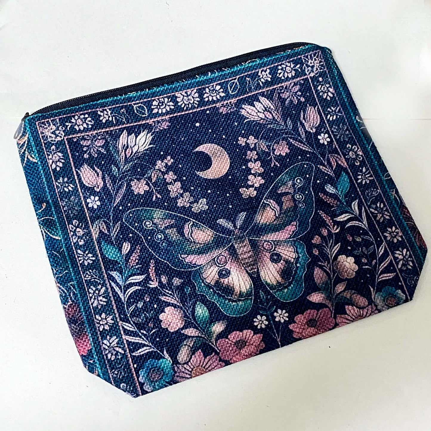 dark botanical canvas pouch with floral and moth illustration and zip closure