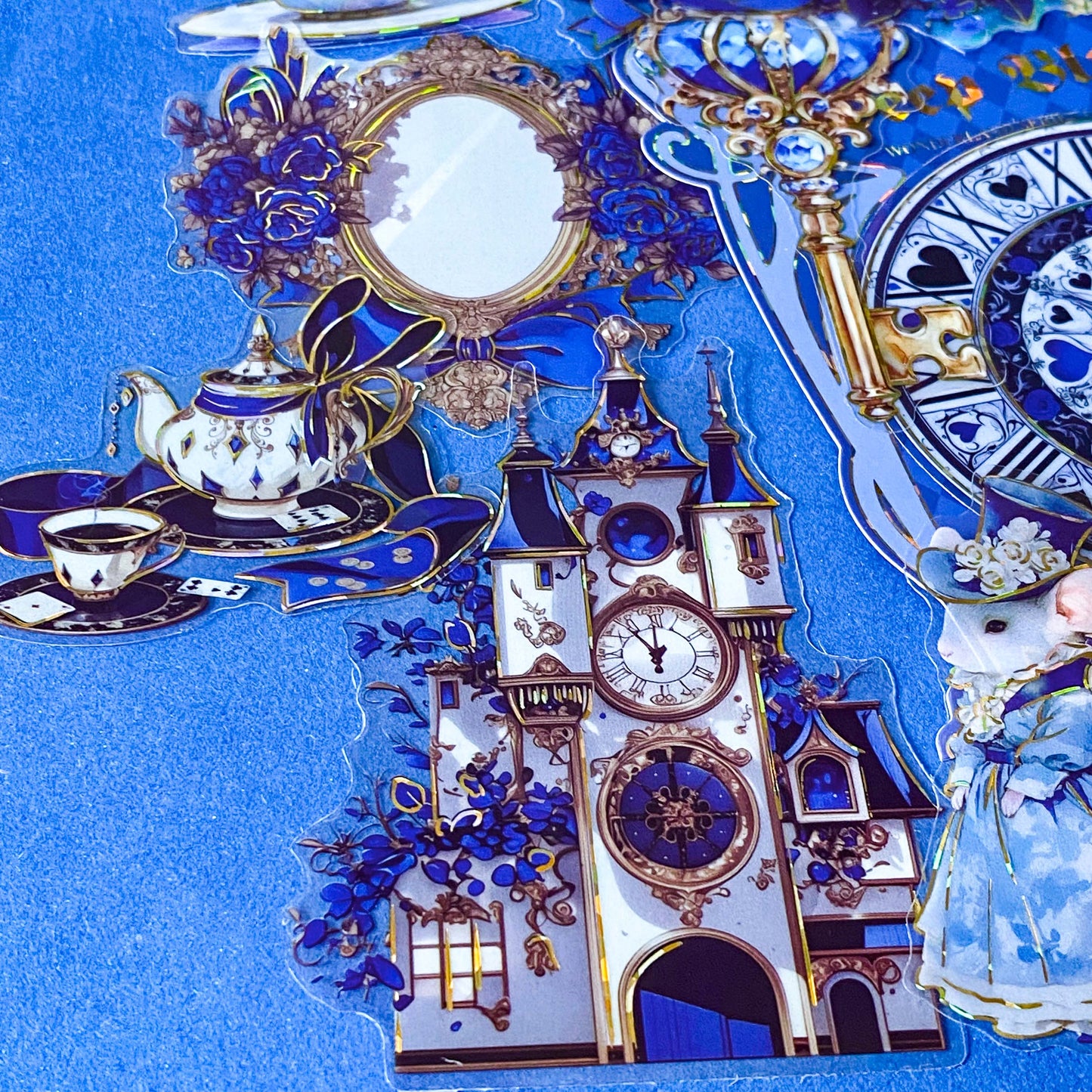 large blue alice in wonderland laser holo holographic plastic stickers featuring white rabbit, alice, clocks, teacups and fantasy illustrations