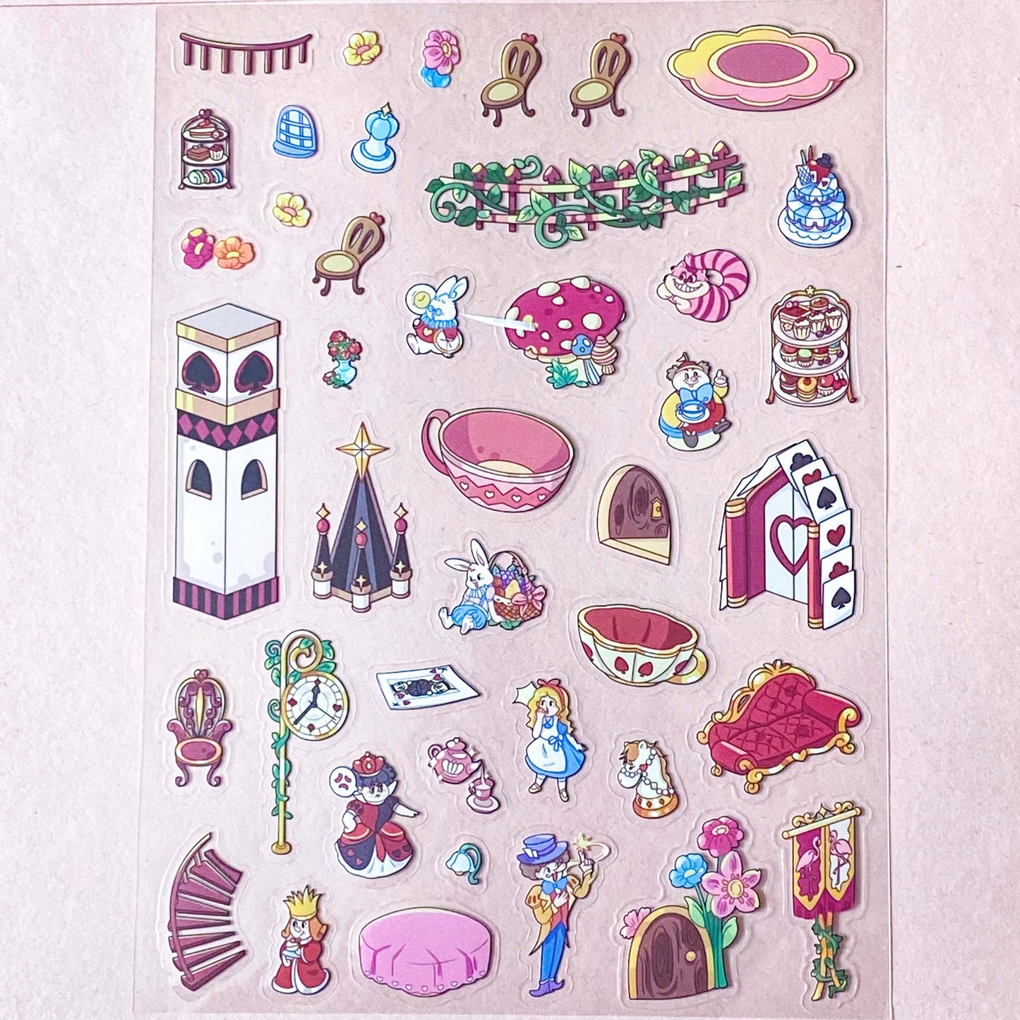 alice in wonderland sticker scene set with background card sheet and clear decorative stickers including teacup, playing cards and fantasy objects. activity creative set