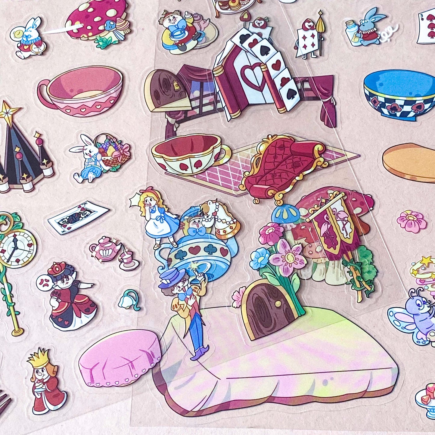alice in wonderland sticker scene set with background card sheet and clear decorative stickers including teacup, playing cards and fantasy objects. activity creative set