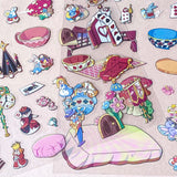 alice in wonderland sticker scene set with background card sheet and clear decorative stickers including teacup, playing cards and fantasy objects. activity creative set