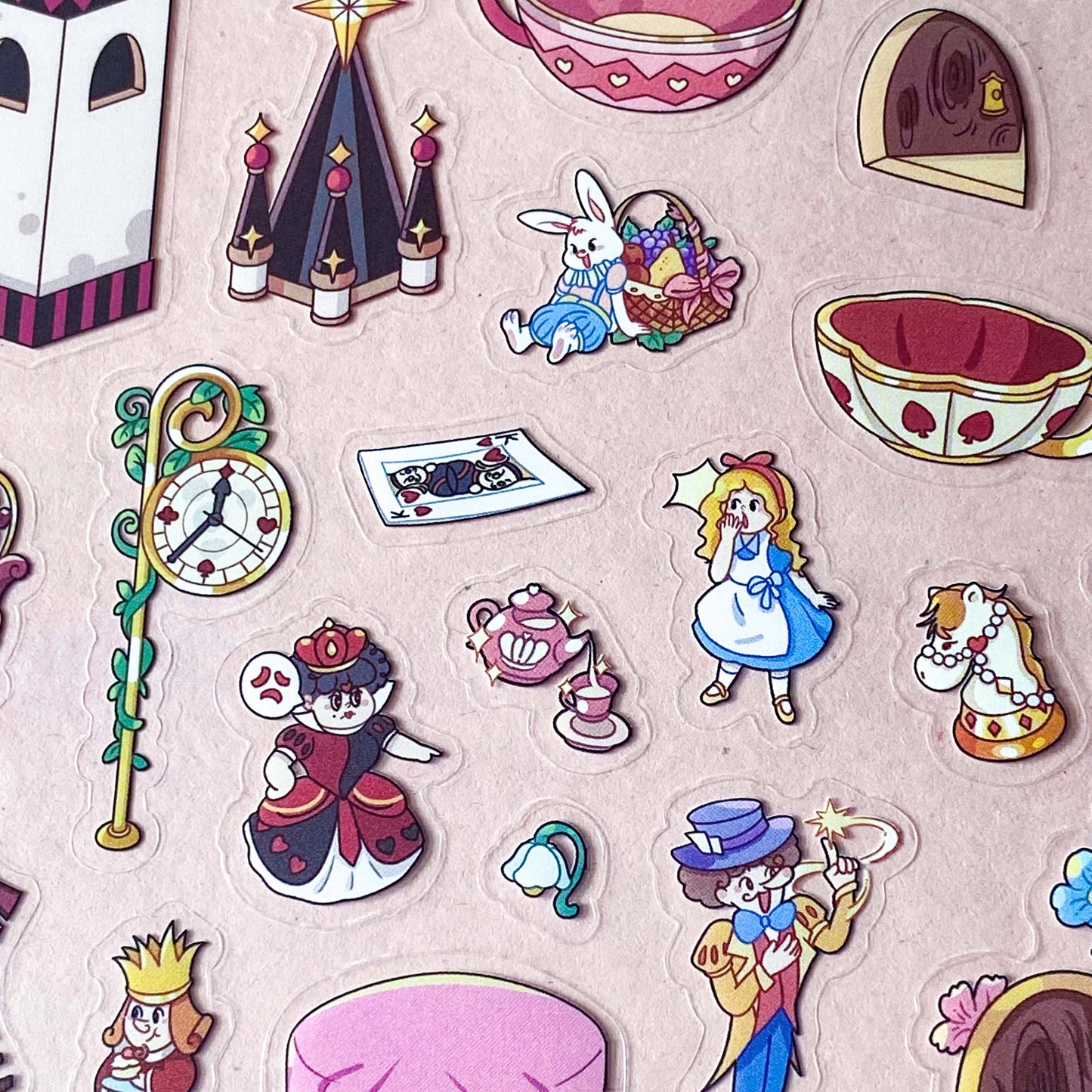 alice in wonderland sticker scene set with background card sheet and clear decorative stickers including teacup, playing cards and fantasy objects. activity creative set