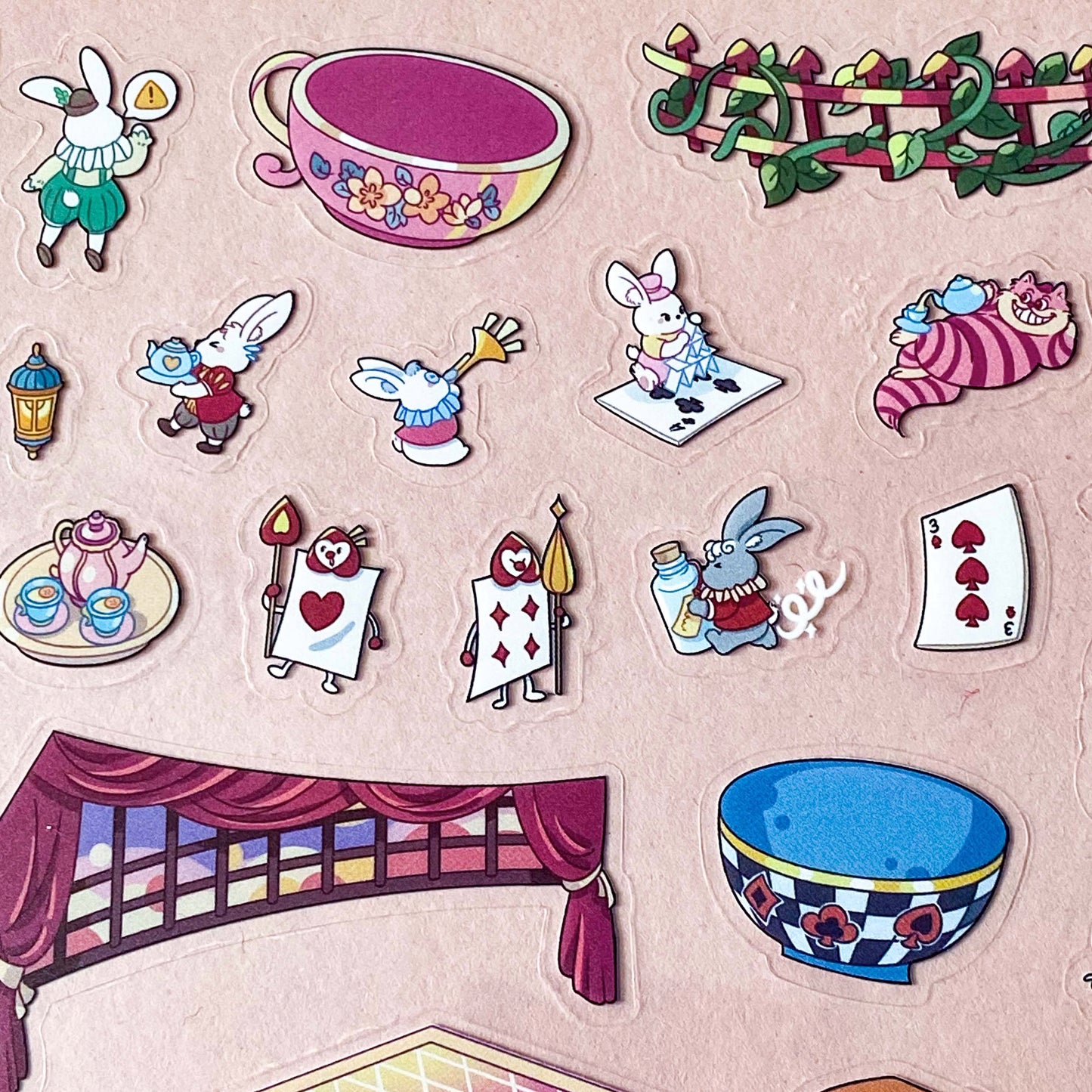 alice in wonderland sticker scene set with background card sheet and clear decorative stickers including teacup, playing cards and fantasy objects. activity creative set