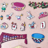 alice in wonderland sticker scene set with background card sheet and clear decorative stickers including teacup, playing cards and fantasy objects. activity creative set