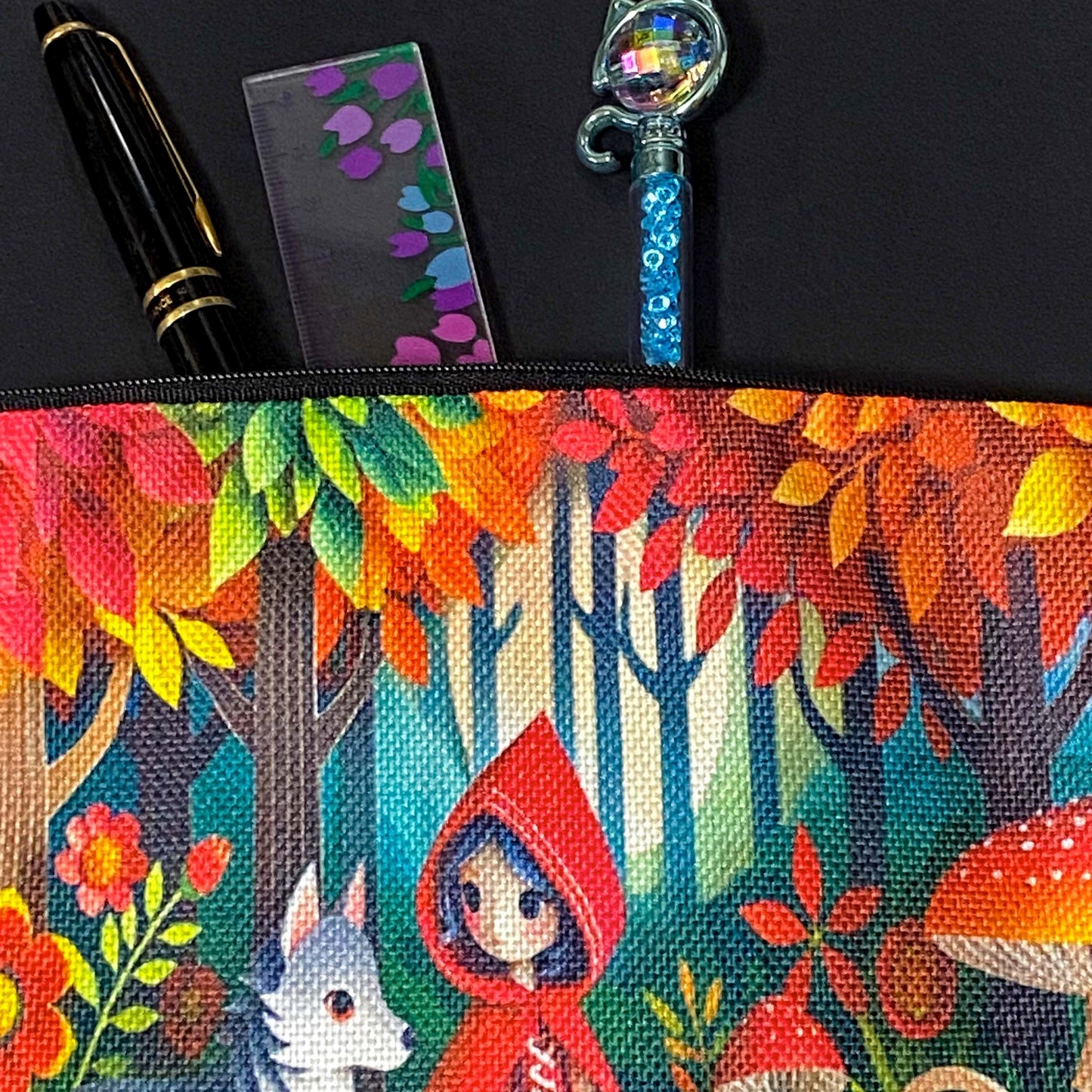 little red riding hood themed canvas zip pouch featuring colourful woodland mushrooms, autumn trees, flowers and a grey wolf companion in a storybook forest scene. red, orange, yellow and lime green colourful gift bag. 