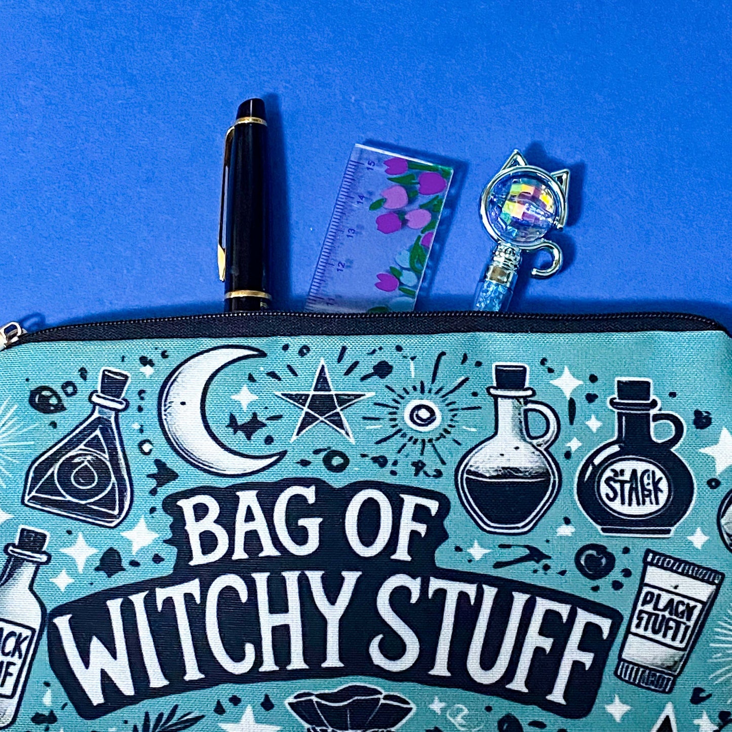 turquoise and black canvas zip pouch featuring the words "Bag of witchy stuff" surrounded by potion bottles, moons, stars, crystals and magical symbols. Uk cute and kawaii gifts shop. Bag for journaling, crystal storage or witchcraft supplies.
