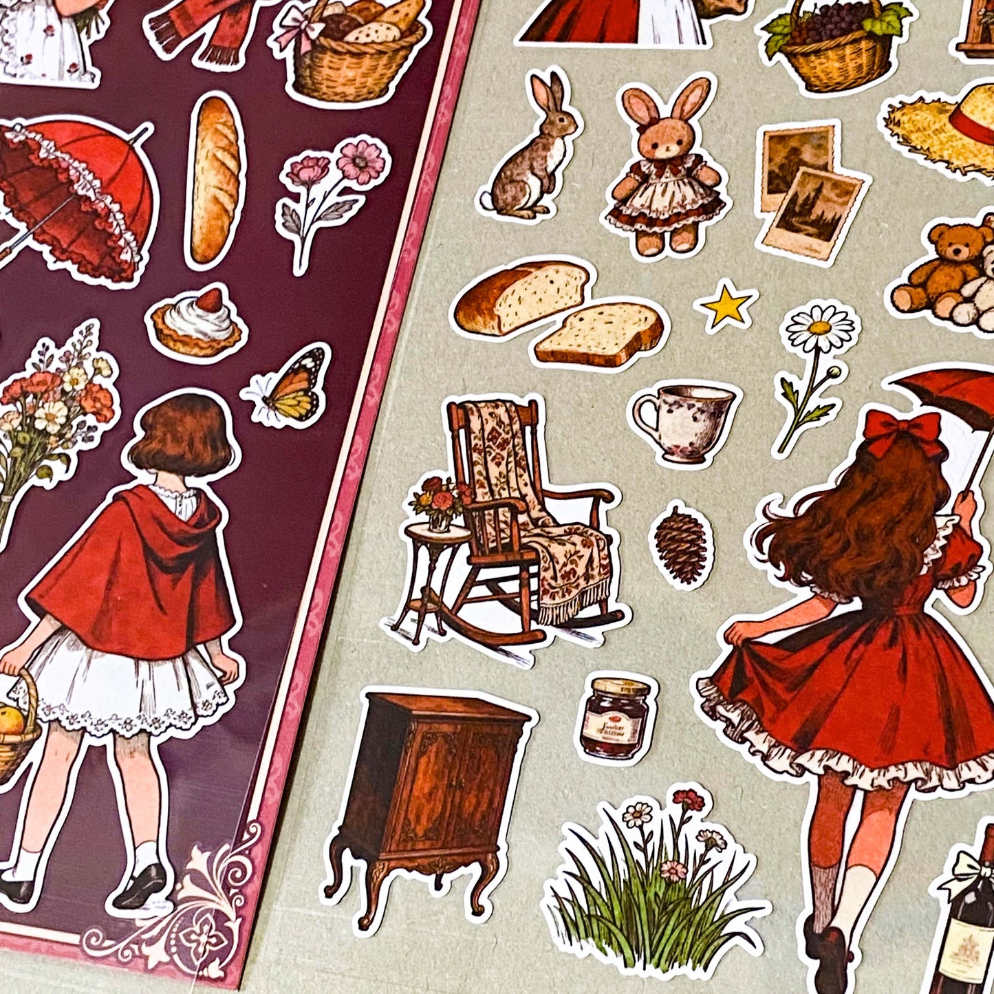 red riding hood's cottage matte sticker pack with two decorative clear sheets of stickers featuring little red riding hood, woodland animals, cottages, flowers, baskets, books, strawberries, squirrels, rabbits and cosy cottagecore illustrations.