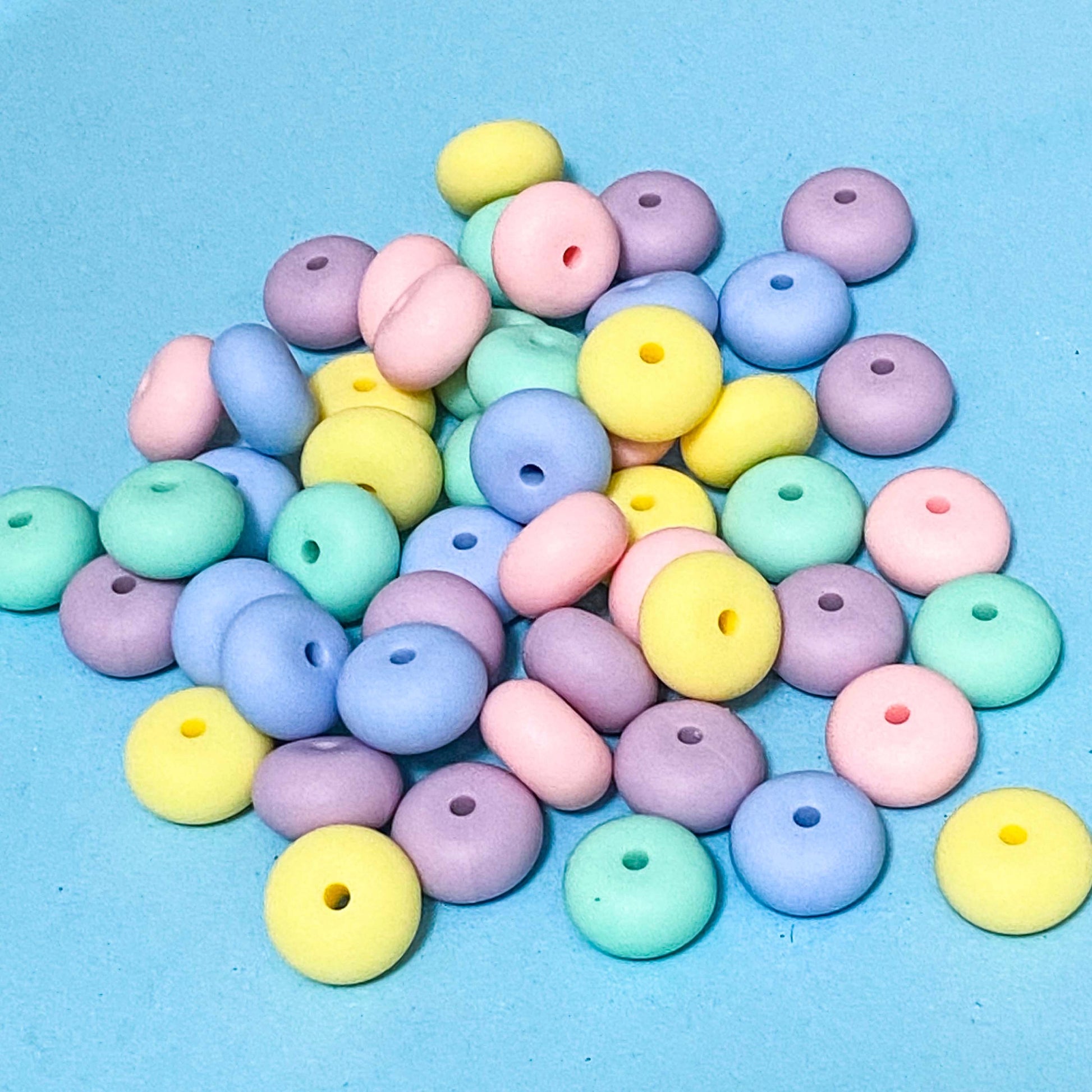 soft silicone abacus beads in pretty spring pastel colours on a blue background