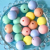 Pastel-colored round 16mm silicone soft beads on a blue plate with a clear bead border