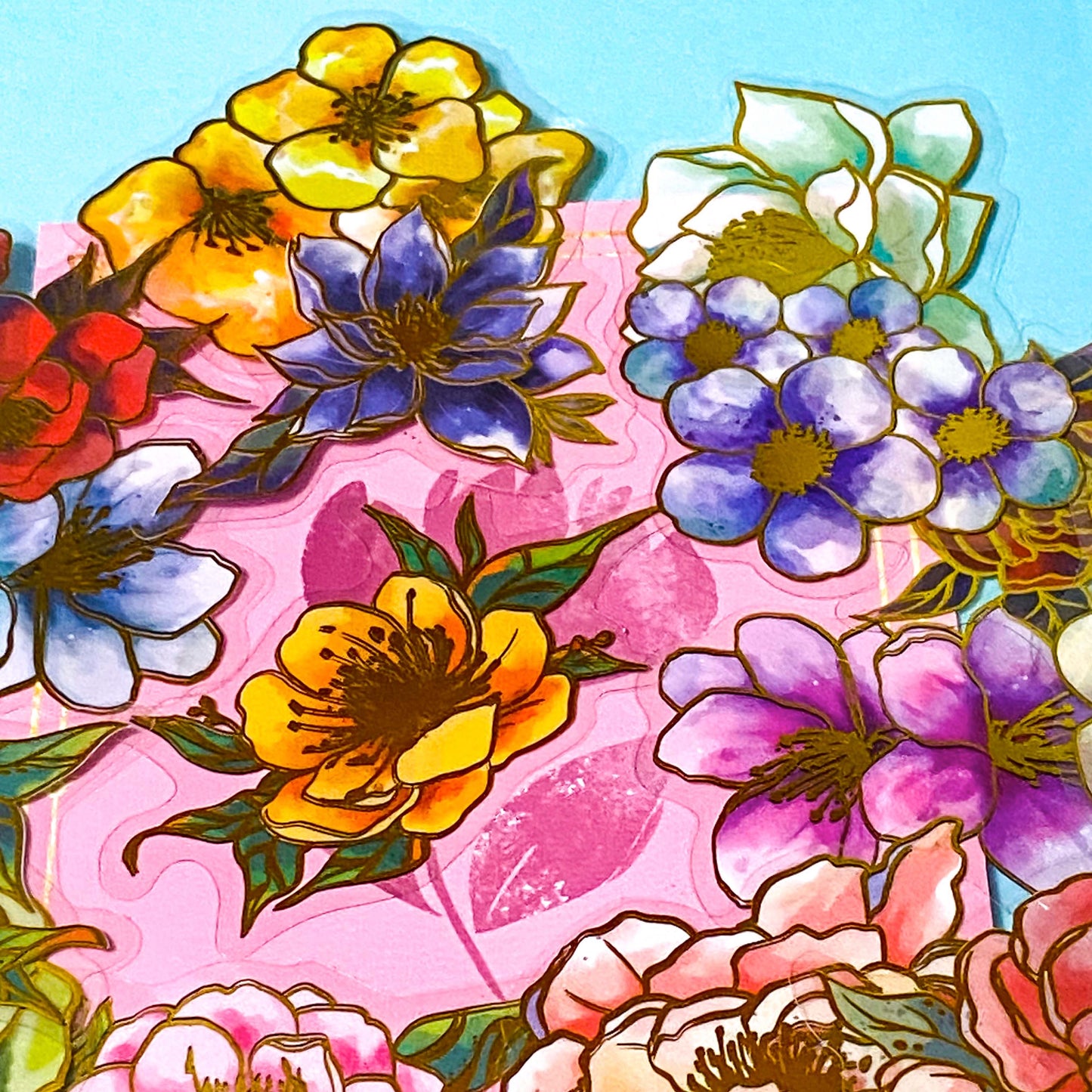 assorted large gold foil floral stickers on a turquoise and pink background