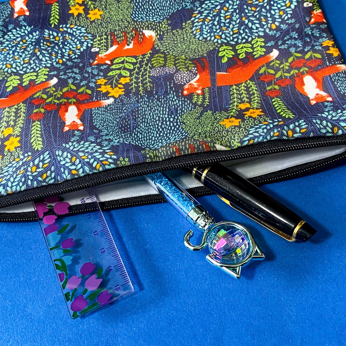 midnight fox hollow canvas fabric pouch featuring orange foxes among wildflowers and trees on a navy background. Zip make up cosmetic bag or journaling pouch. UK cute gift shop.