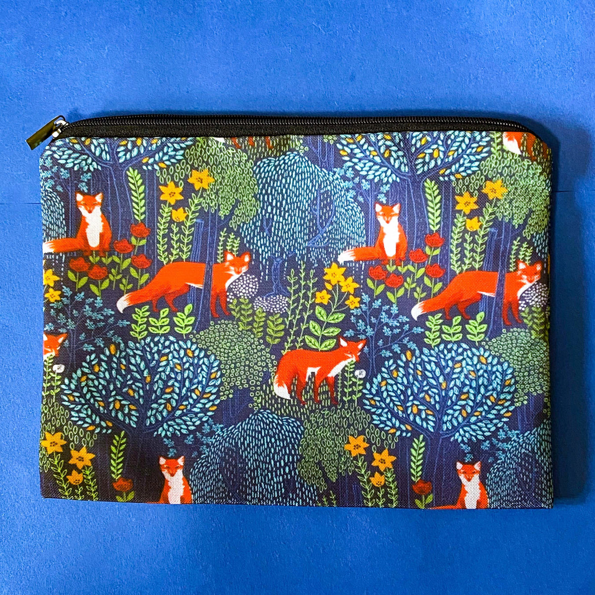 midnight fox hollow canvas fabric pouch featuring orange foxes among wildflowers and trees on a navy background. Zip make up cosmetic bag or journaling pouch. UK cute gift shop.