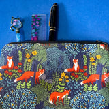 midnight fox hollow canvas fabric pouch featuring orange foxes among wildflowers and trees on a navy background. Zip make up cosmetic bag or journaling pouch. UK cute gift shop.