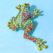 jewelled rhinestone green frog metal brooch on a blue background