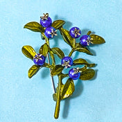 blueberry Brooch with blue berries and green leaves on a light blue background