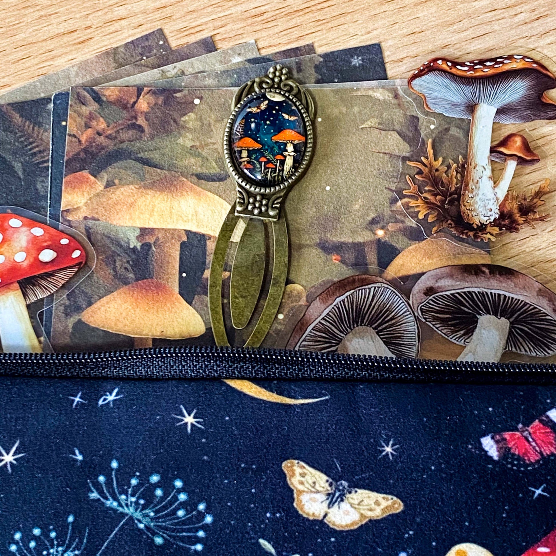 mushroom themed gift set with lined canvas pouch, vintage style bookmark, woodland scrapbook papers and clear mushroom stickers on wooden background