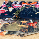 mushroom themed gift set with lined canvas pouch, vintage style bookmark, woodland scrapbook papers and clear mushroom stickers on wooden background