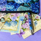 blue hydrangea letterbox gift set with canvas floral pouch, hydrangea black ink pen, enamel blue flower metal brooch, vintage botanical postcards and clear hydrangea stickers. uk cute gifts shop.