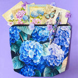 blue hydrangea letterbox gift set with canvas floral pouch, hydrangea black ink pen, enamel blue flower metal brooch, vintage botanical postcards and clear hydrangea stickers. uk cute gifts shop.