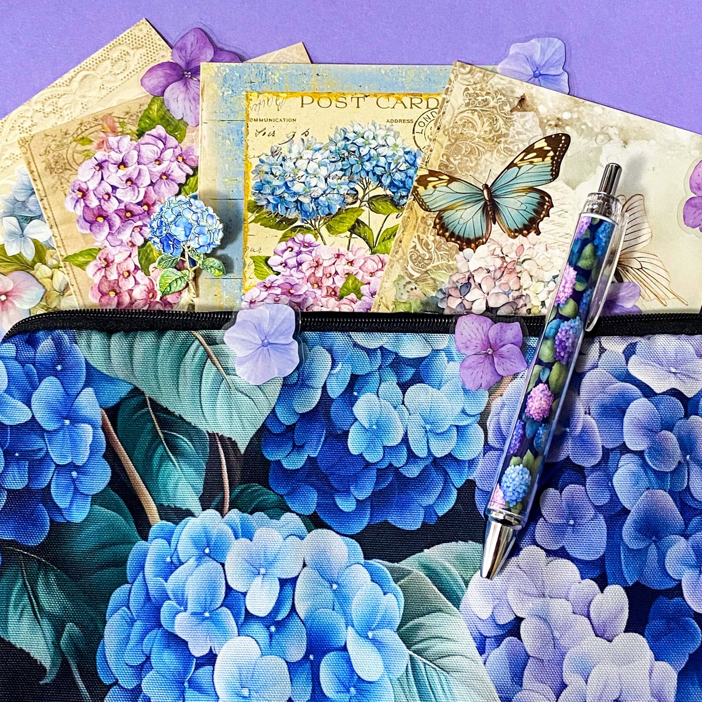 blue hydrangea letterbox gift set with canvas floral pouch, hydrangea black ink pen, enamel blue flower metal brooch, vintage botanical postcards and clear hydrangea stickers. uk cute gifts shop.