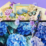 blue hydrangea letterbox gift set with canvas floral pouch, hydrangea black ink pen, enamel blue flower metal brooch, vintage botanical postcards and clear hydrangea stickers. uk cute gifts shop.