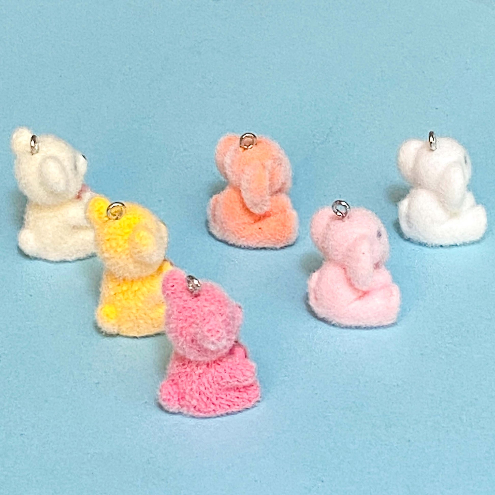 teddy bear and elephant resin flocked charms on a blue background