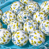 White silicone beads with yellow and blue floral patterns on a blue plate