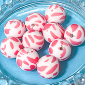 pink and white abstract leopard print patterned silicone beads on a blue background