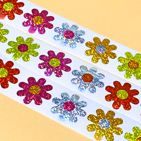 Big Colourful flower-shaped daisy glitter stickers on a white backing with a yellow background