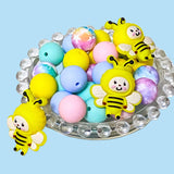 large yellow silicone bee beads with round pastel coloured beads on a blue background
