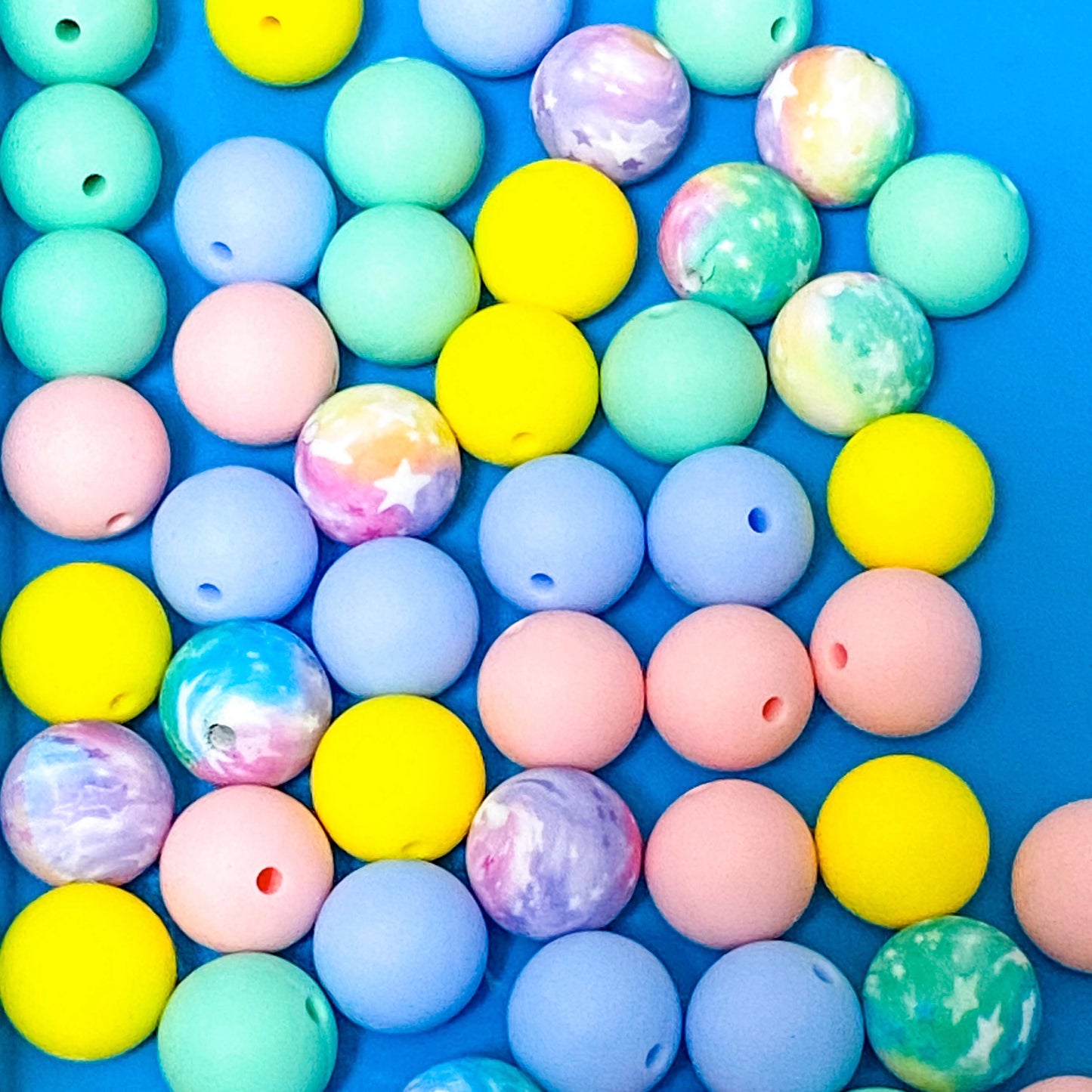 Pastel-coloured round silicone 16mm beads on a blue background