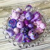 large purple and lilac acrylic and silicone beads bundle of 22 with designs including bear, cat, hot air balloon and bow. For making beaded pens and jewellery. `uk crafts bundle. Pretty beading kit.