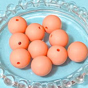 pastel peach silicone 15mm round soft beads on a blue background