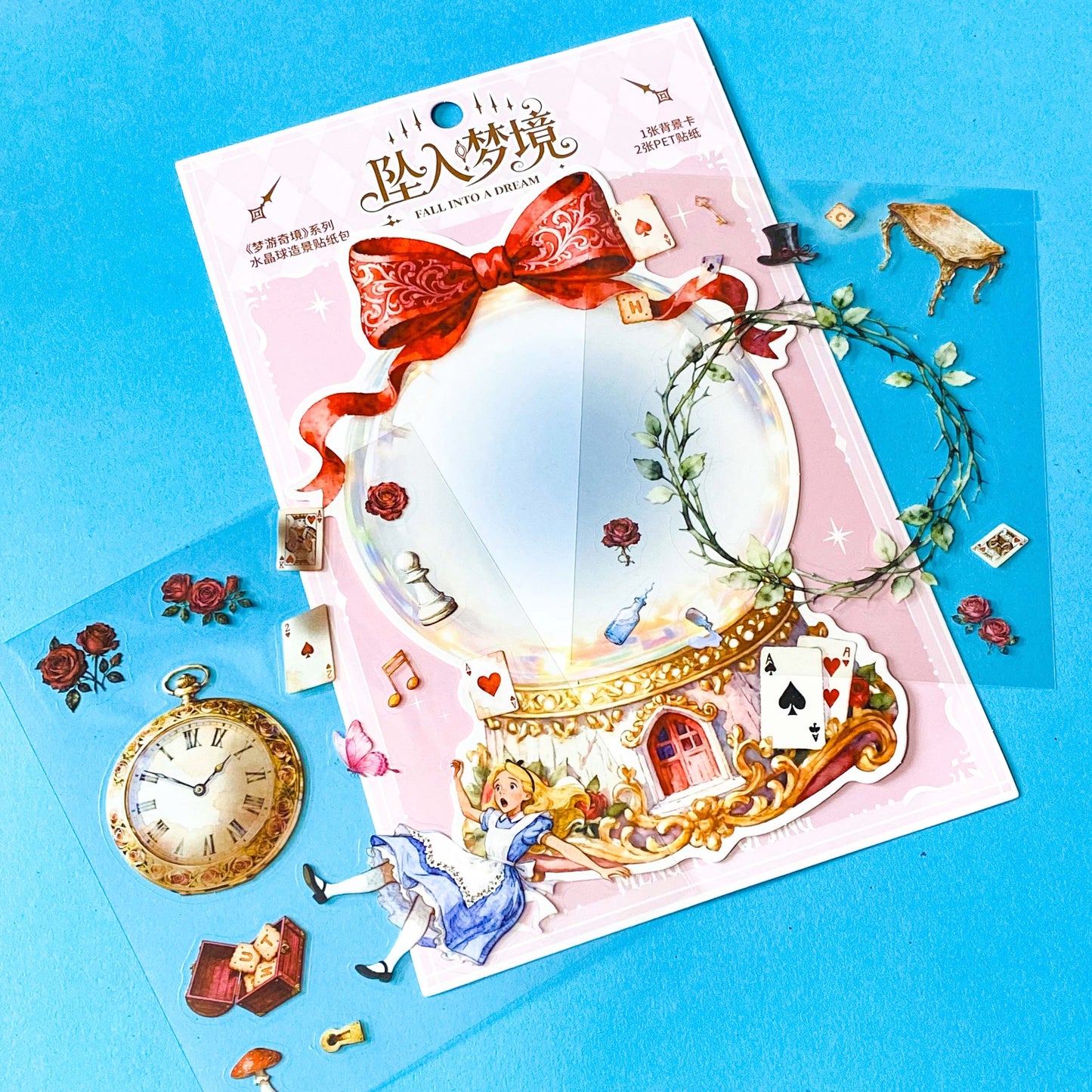 large alice inspired falling into wonderland sticker set with oversized now globe scene card, transparent PET stickers, pocket watch, roses and playing cards details on pink backing card with bow