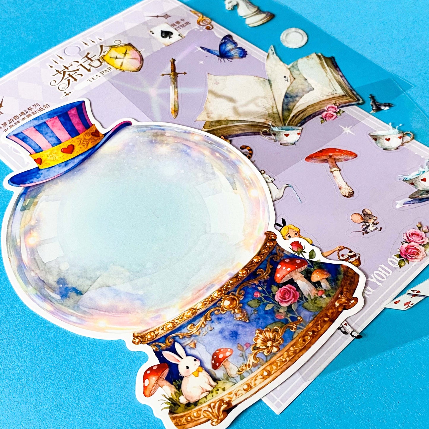 alice inspired mad hatter tea party snow globe PET sticker scene set with transparent stickers, card scene and teacups, books, mushrooms and cheshire cat illustrations